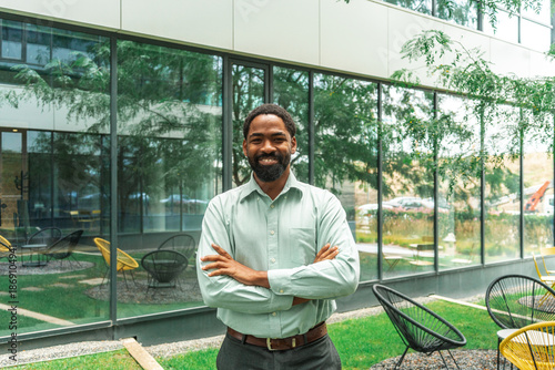 Confident Businessman In Green Shirt Stands With Arms Crossed 