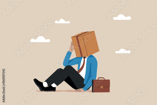 Businessman with a box on his head sitting on the ground feeling overwhelmed and stressed