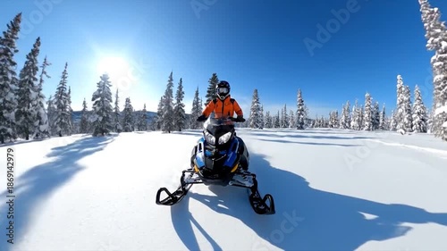 A person on a blue and yellow snowmobile speeding through a snowy forest under a clear sky