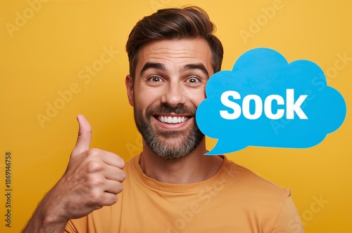 Happy Man Holding Blue Speech Bubble with Text and Showing Thumbs Up Gesture Against Yellow Background