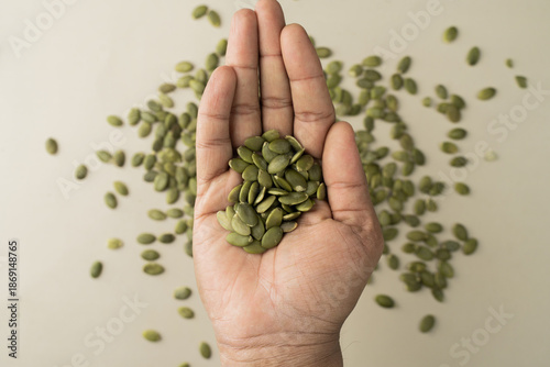 Green Pumpkin seeds are placed on a hand.