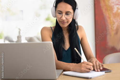 Foto Focused young New Zealander female student in wireless headphones and eyeglasses