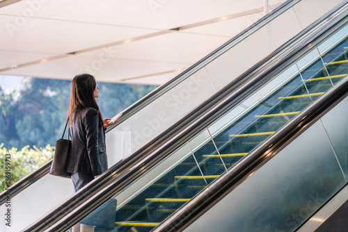 Japanese businesswoman riding escalator in modern city building
