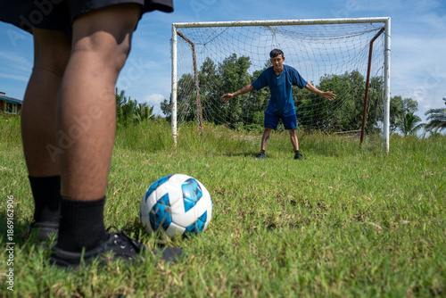 Two man playing a game of soccer in a country. Group of young adults is running after a soccer ball on a grass field on a sunny summer day.