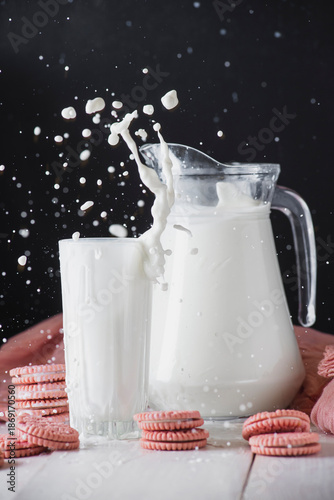 Cuadro en lienzo Milk splash rising from glass and jug on black background, high speed dairy phot