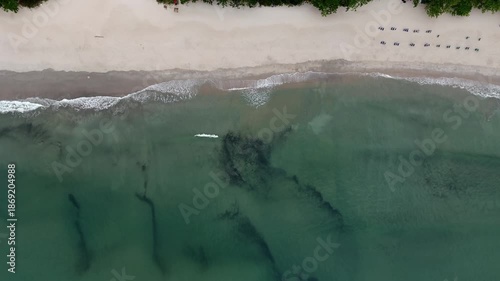 Movement of ocean waves on deserted white sand beach. Aerial birdseye descendant