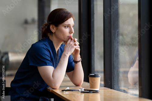 Bilde på lerret Tired female doctor or nurse with stethoscope looking out window, thinking in cafe
