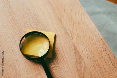 Magnifying glass focusing on Love word for Valentine's Day concept, searching for soulmate and romantic discovery on wooden background.