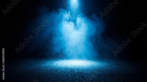 Dramatic blue spotlight shining through smoke on dark asphalt floor