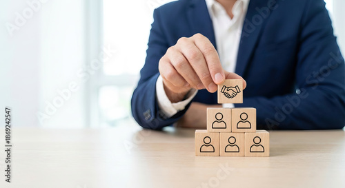 Businessman hand placing handshake block on person icon pyramid for team collaboration
