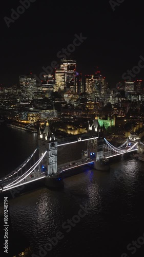 Vertical aerial view of London skyline at night. Beautiful view of Tower Bridge and the City of London illuminated by city lights