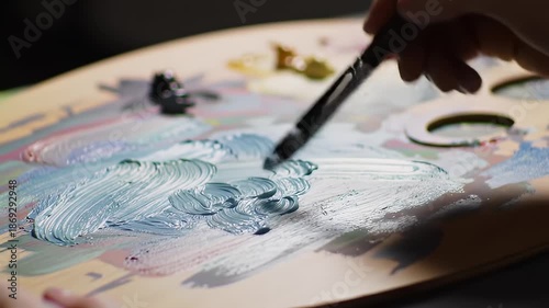 Artist Hand Holding Brush Mixing Blue and White Oil Paints on Wooden Palette Creating Abstract Artwork Gentle Strokes Gentle Lighting Inspiring Creativity