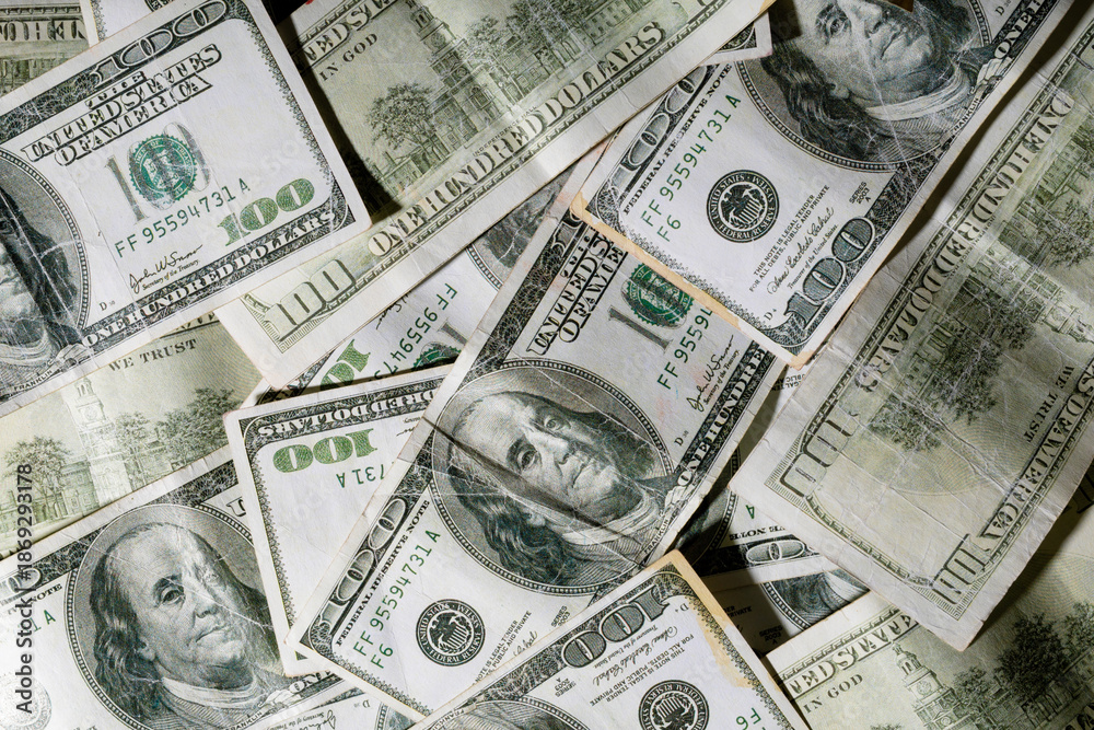 Fototapeta premium Overhead view of scattered hundred dollar bills with famous historic personality