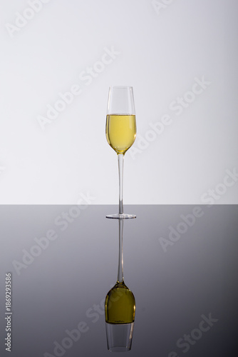 Closeup of champagne flute with reflection on glass table, drink against white background