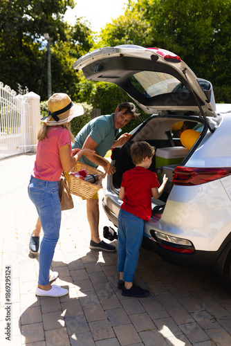 Happy caucasian family loading their luggage in their car outdoors