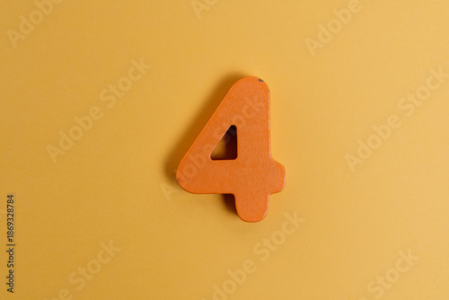Orange wooden number four representing concepts of learning, education, and childhood numeracy