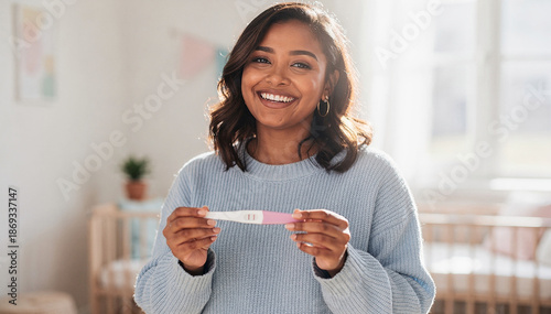 Cheerful african american woman holding pregnancy test and looking at camera