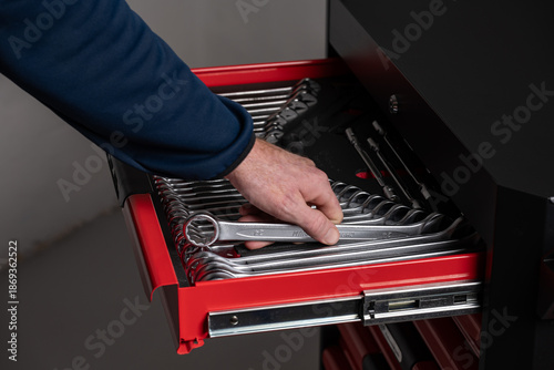Fotografie Hand selecting wrench from organized tool drawer