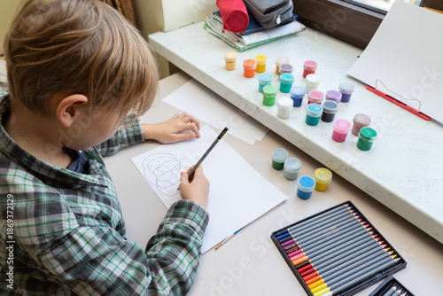Billede på lærred Little boy drawing with pencil on paper at table