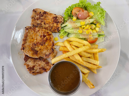 Grilled chicken served with french fries, fresh salad and sauce, casual western meal concept