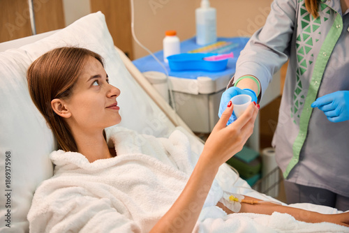 фотографія Woman lying in bed while nurse hands medication