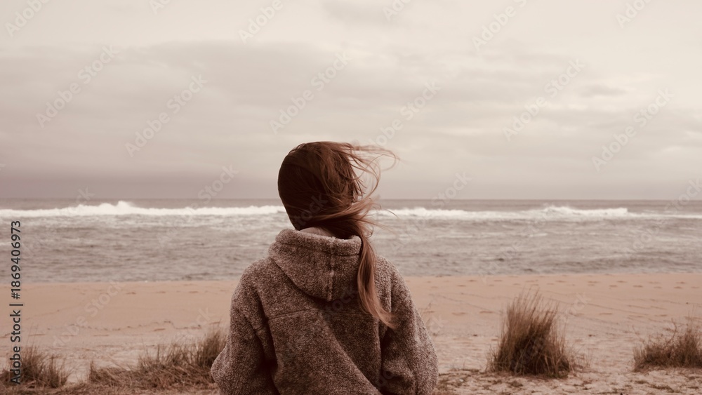 Αυτοκόλλητο Young woman contemplating the sea on a windy beach