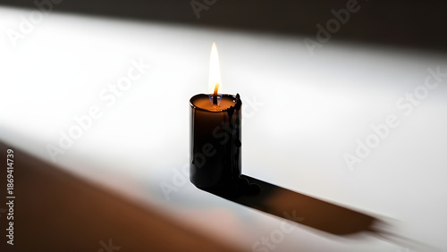 A burning candle casting a shadow. A symbol of warmth, hope, and light, perfect for evoking a sense of calm and reflection. 