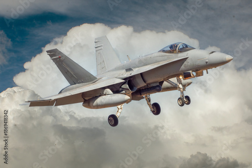 Avión de combate maniobrando para aterrizar con fondo de nubes.