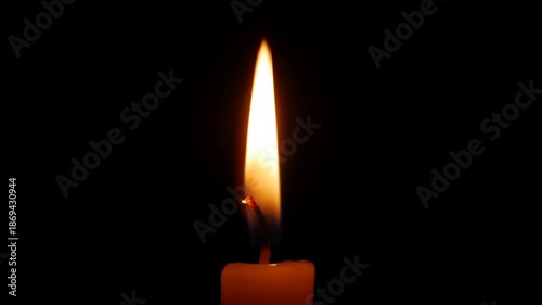 A warm glow rises from a candle in wide darkness as soft flicker captures the slow passage of tenderness absence and the emotional strain of remembering. Memory sorrow.
