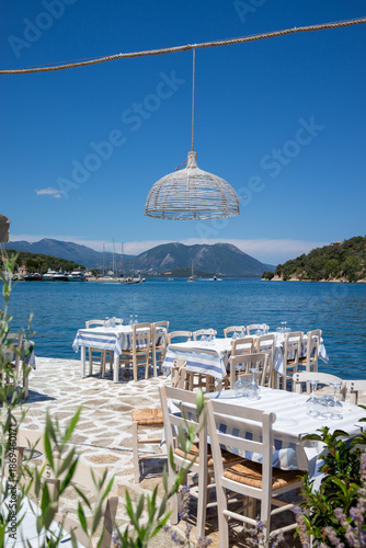 Served tables in a Greek tavern in Vathy Harbor, Meganisi island, Ionian Sea, Greece during the summer tourist season. 