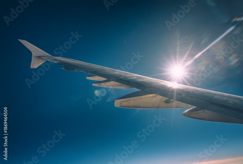Commercial airplane wing with sleek metallic surface flying in clear blue sky during daytime