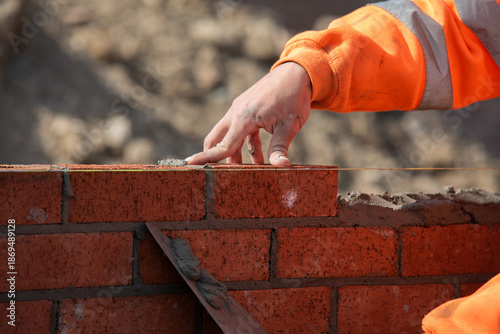 Bild auf Leinwand Bricklayer laying red bricks on construction site