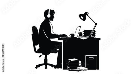 Silhouette of a focused worker wearing headphones typing intently on a laptop at a busy desk