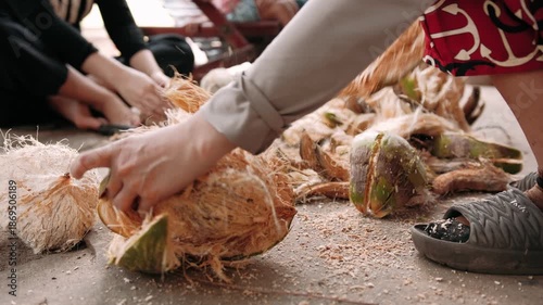 Close up of cutting a coconut with knife. Green fresh coconut peeling and shelling with heavy chop knife for juice.