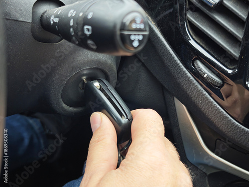 Hand turning car key in ignition switch inside vehicle interior, close-up automotive detail, engine start, transportation and driving routine