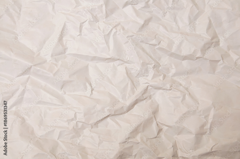 Naklejka premium Close-up texture of crumpled off-white paper with deep shadows and highlights