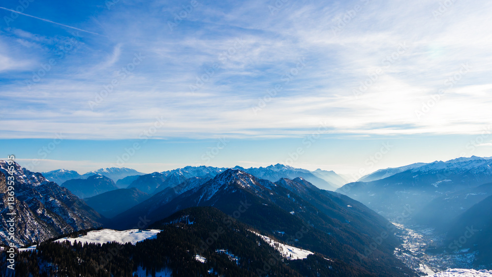 Fototapeta premium View to Pinzolo village in the valley of Italian Alps mountains during ski resort winter season, sport and tourism