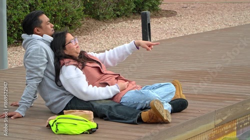 Full shot of an asian couple on a romantic moment  sitting on a park	
