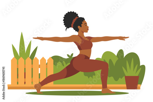 Woman performs warrior two yoga pose outdoors near a wooden fence in.