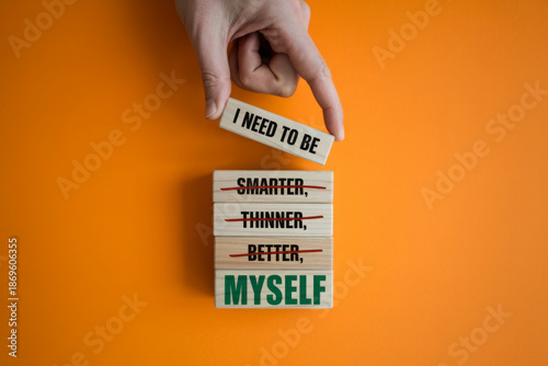Be myself symbol. Businessman hand. Wooden blocks with words 'i need to be myself, not smarter, thinner, prettier, better'. Beautiful orange background, copy space. Psychological, be myself concept.