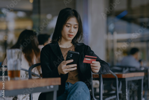 Obraz na plátne Young asian woman using phone and credit card online shopping for ordering food, or buying something at cafe