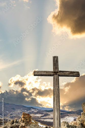 Christian cross on the top of hill, barren field in winter. Holy cross on the hill for pilgrimage, devotion, faith