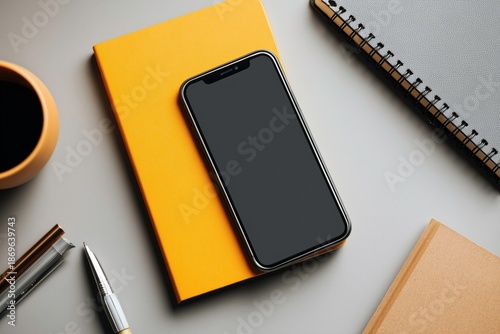 smartphone on a yellow paper notebook on clean desk, minimal business workspace