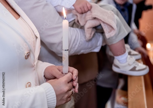 Women's hands holding a candle during a baptism ceremony