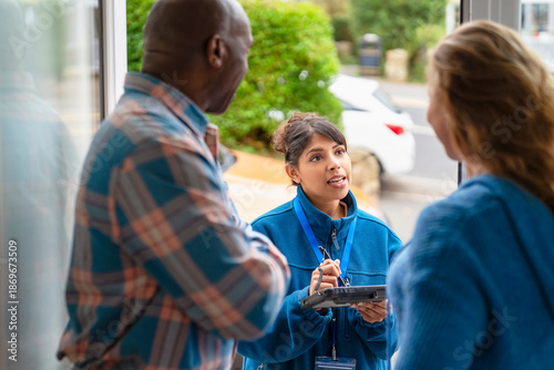 Community service worker interacts with two residents outside a building during the day