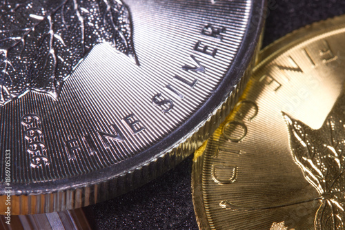 Close-up of the inscription “fine silver” on a silver coin lying on a gold coin labeled “fine gold,” representing precious metal prices and the gold-to-silver ratio.