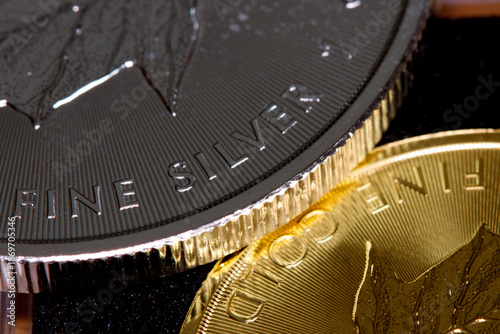 Close-up of the inscription “fine silver” on a silver coin lying on a gold coin labeled “fine gold,” representing precious metal prices and the gold-to-silver ratio.