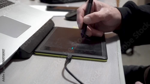 Drawing on a graphics tablet. Male hand. Digital artist. Room. Daylight. Close-up. Faceless. Creativity