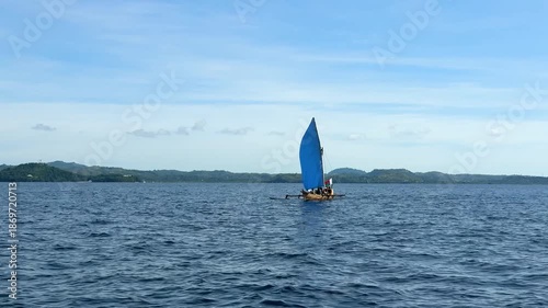 Sailing on a small wooden boat in clear blue water under a bright sky with distant hills present