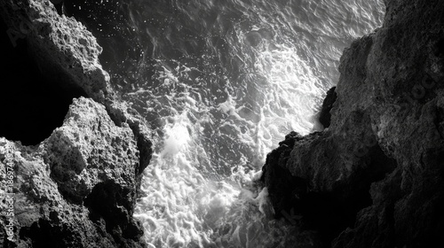A black and white photo of crashing waves against a rocky cliffside.
